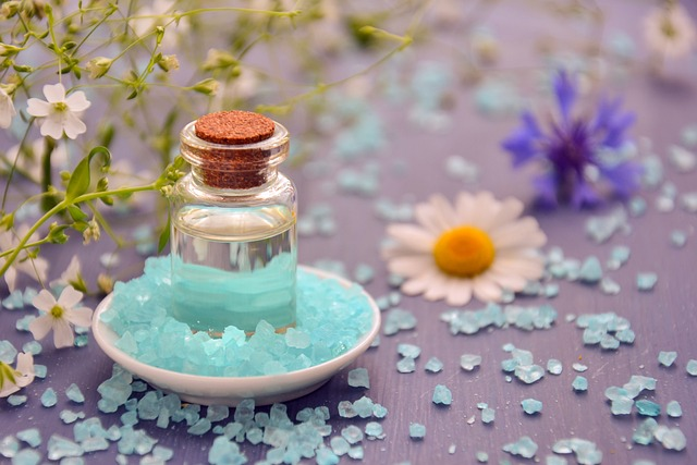 bottle of oil placed near plant and flowers on a table. surrounded by pieces of gem stones.