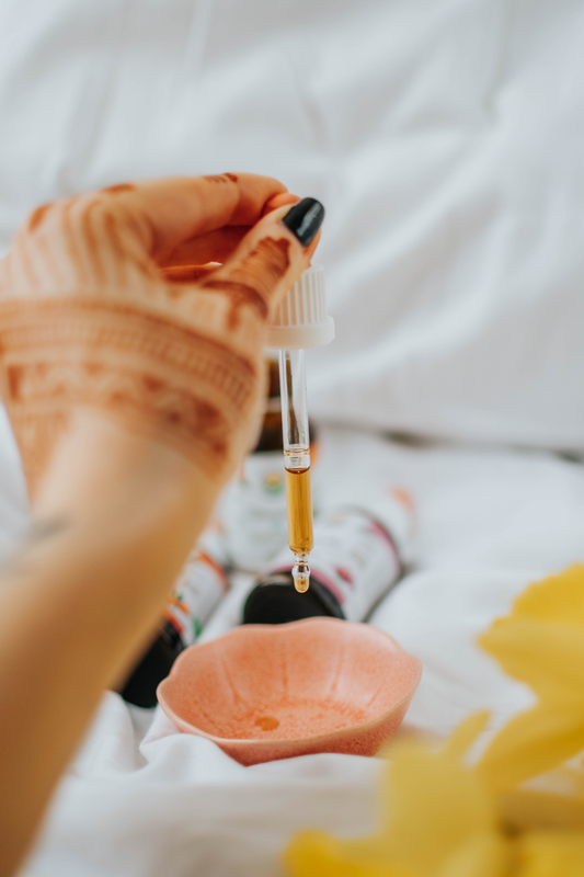 woman with henna tattoo on hand holding a dropper containing essential oil.
