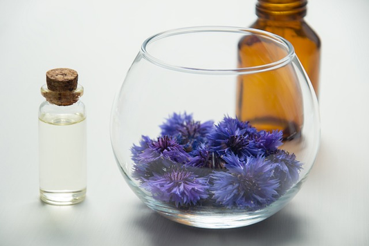 purple flowers in a glass, 2 glass bottles placed on each side of the cup.