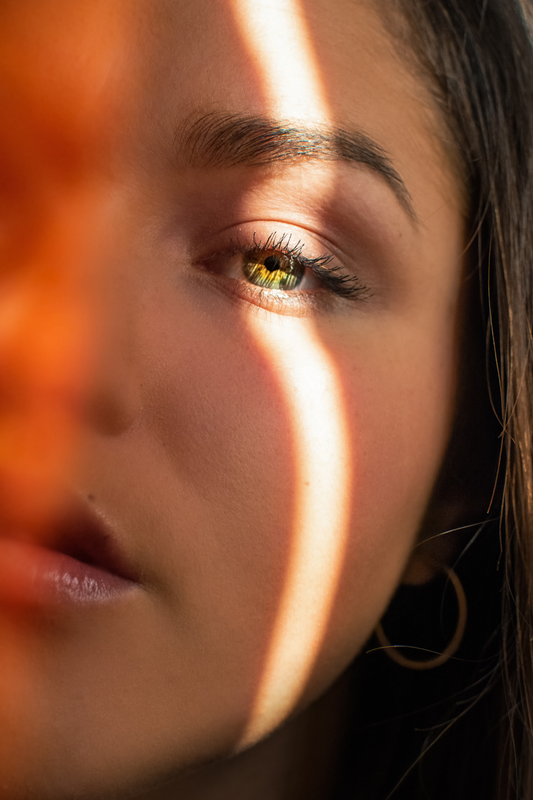 Photo showing one half of the face of a woman with sunlight falling on her face.