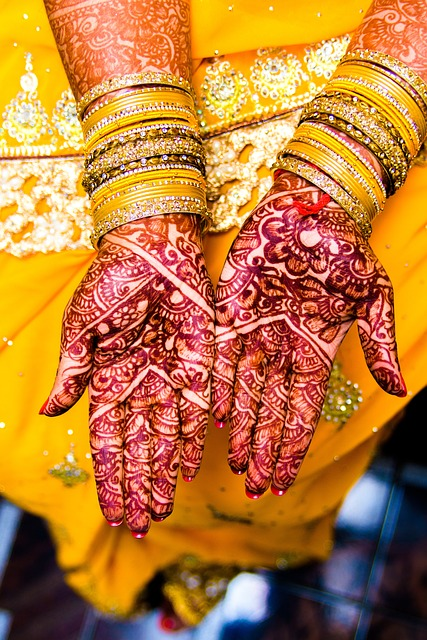 woman's hands with henna tattoo on them wearing bangles.